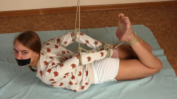 Gagged with a black duct tape barefoot Irene in long-sleeve and shorts, hogtied with hemp rope, wiggles on the floor (HD.webp