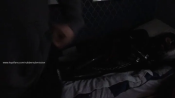 Black Rubber Drone Restrained On The Bed.webp
