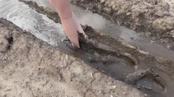 A girl with bare feet walks through sticky deep mud (which version).webp