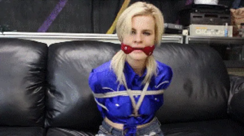 Catie Parker in her shiny cowgirl outfit hogtied and gagged.webp