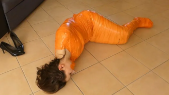 Chloe wriggle mummified in orange tape.webp