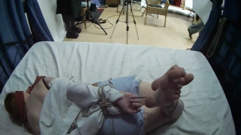 Barefoot blindfolded Amy in white shirt and jeans shorts, hogtied with hemp rope, is tickled and teased by Blackshark.webp